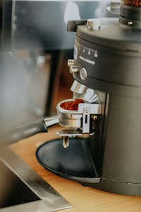 Close-up of a portafilter filled with ground coffee in an espresso machine.