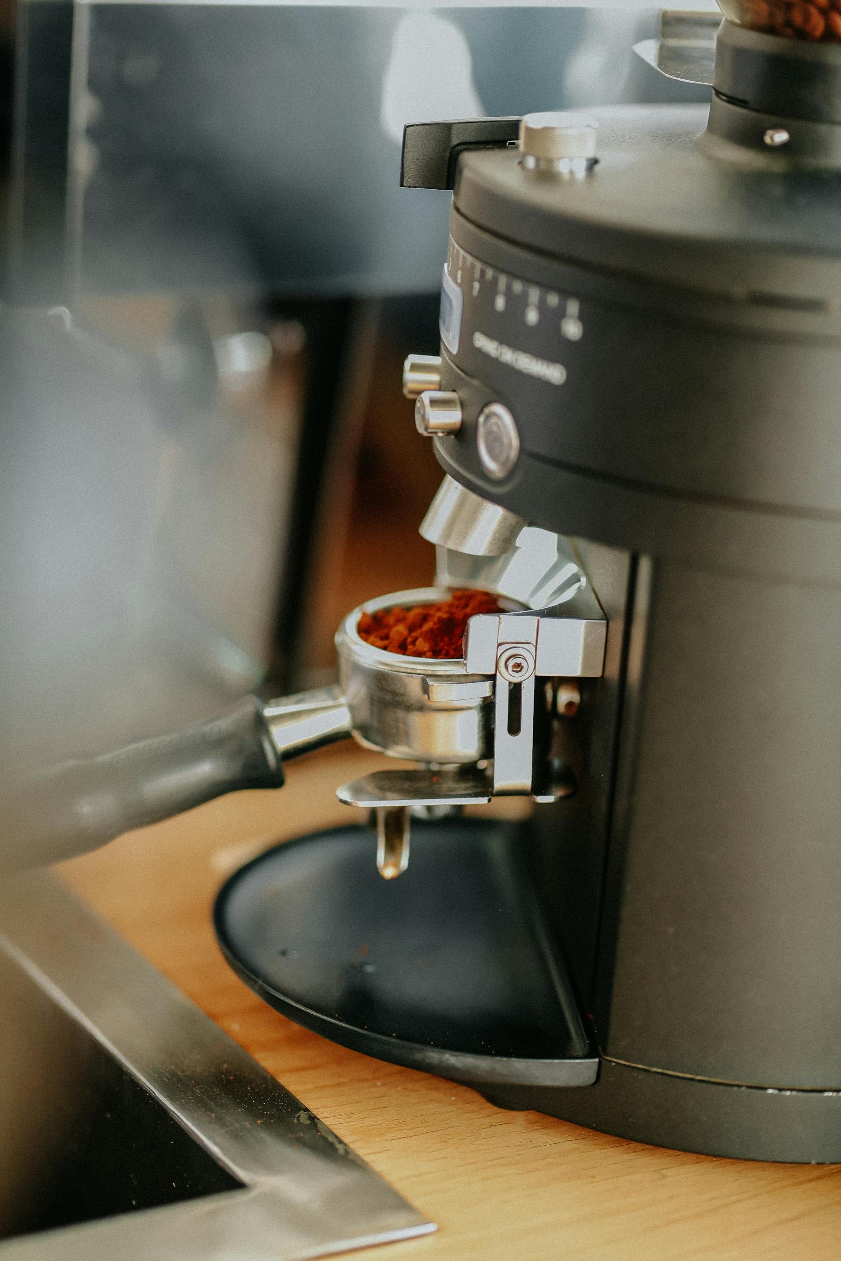 Close-up of a portafilter filled with ground coffee in an espresso machine.