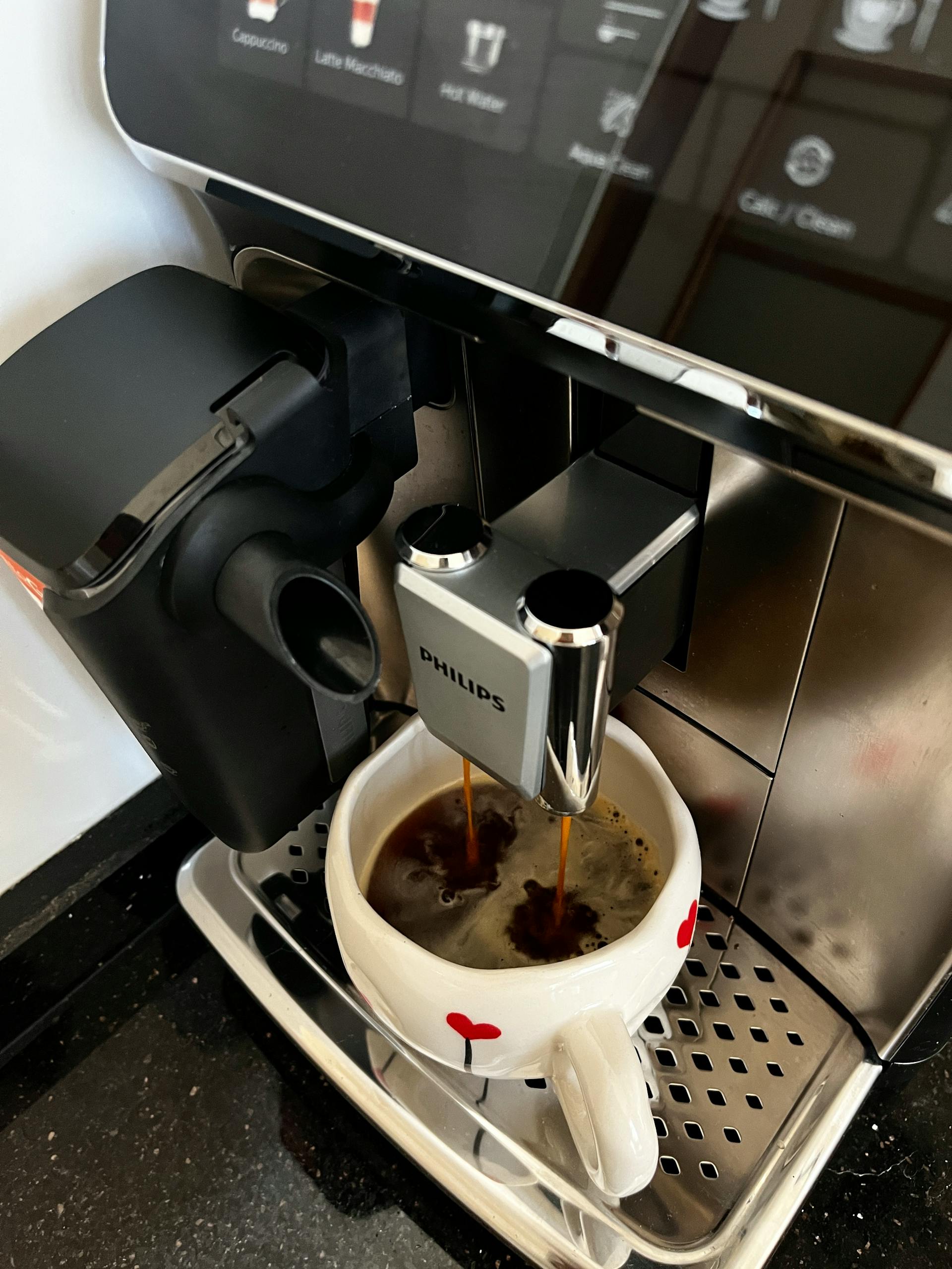 Close-up of coffee brewing in cup using modern espresso machine.