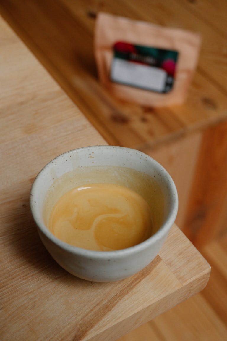 A close-up of a creamy latte in a ceramic cup with specialty coffee beans in the background.