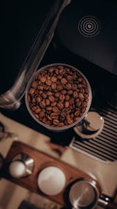 A warm, aesthetic top-view photograph of coffee beans inside an espresso machine grinder.