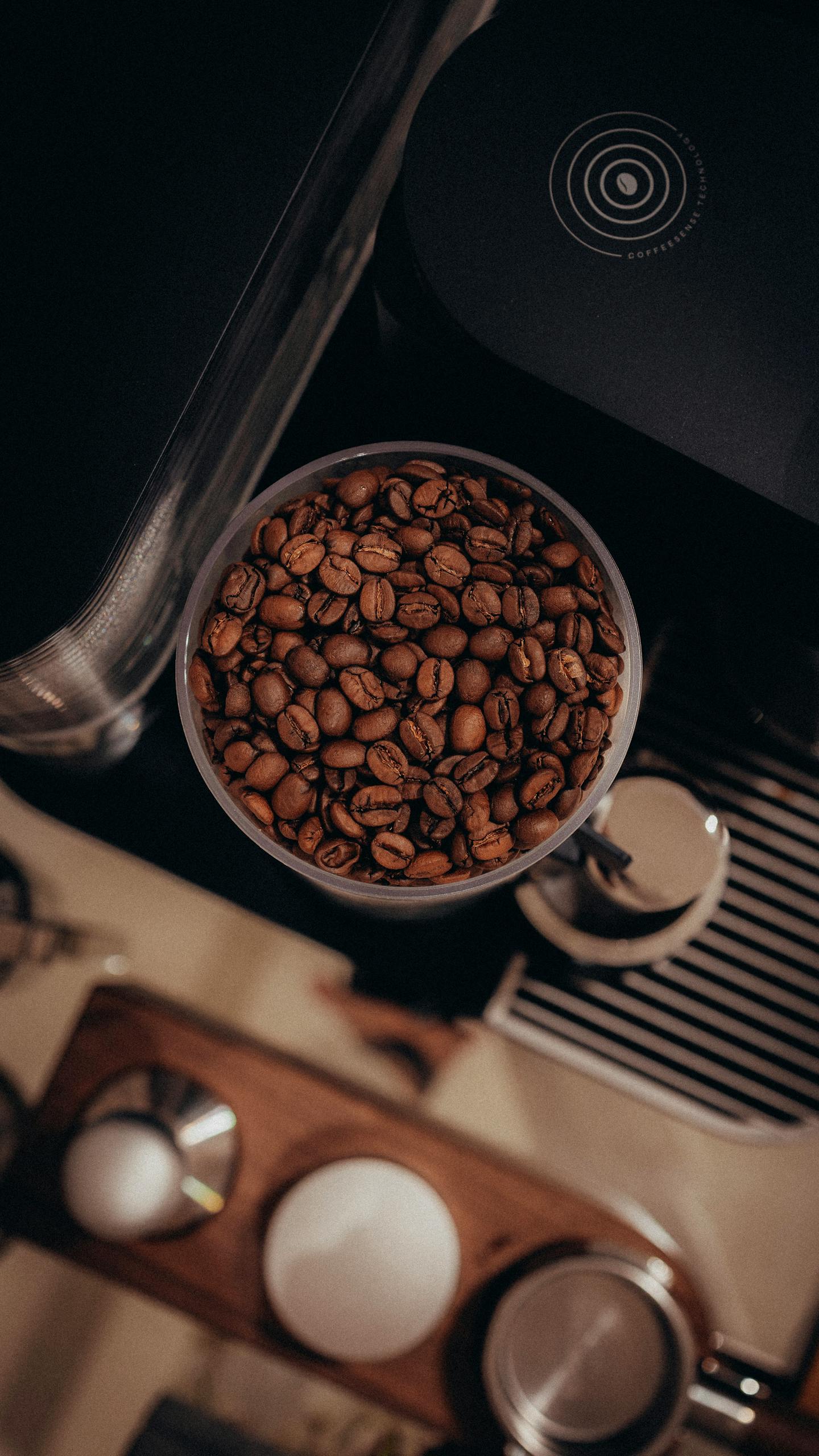 A warm, aesthetic top-view photograph of coffee beans inside an espresso machine grinder.