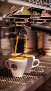 Close-up of espresso being poured into cups from a coffee machine in Izmir, Türkiye.