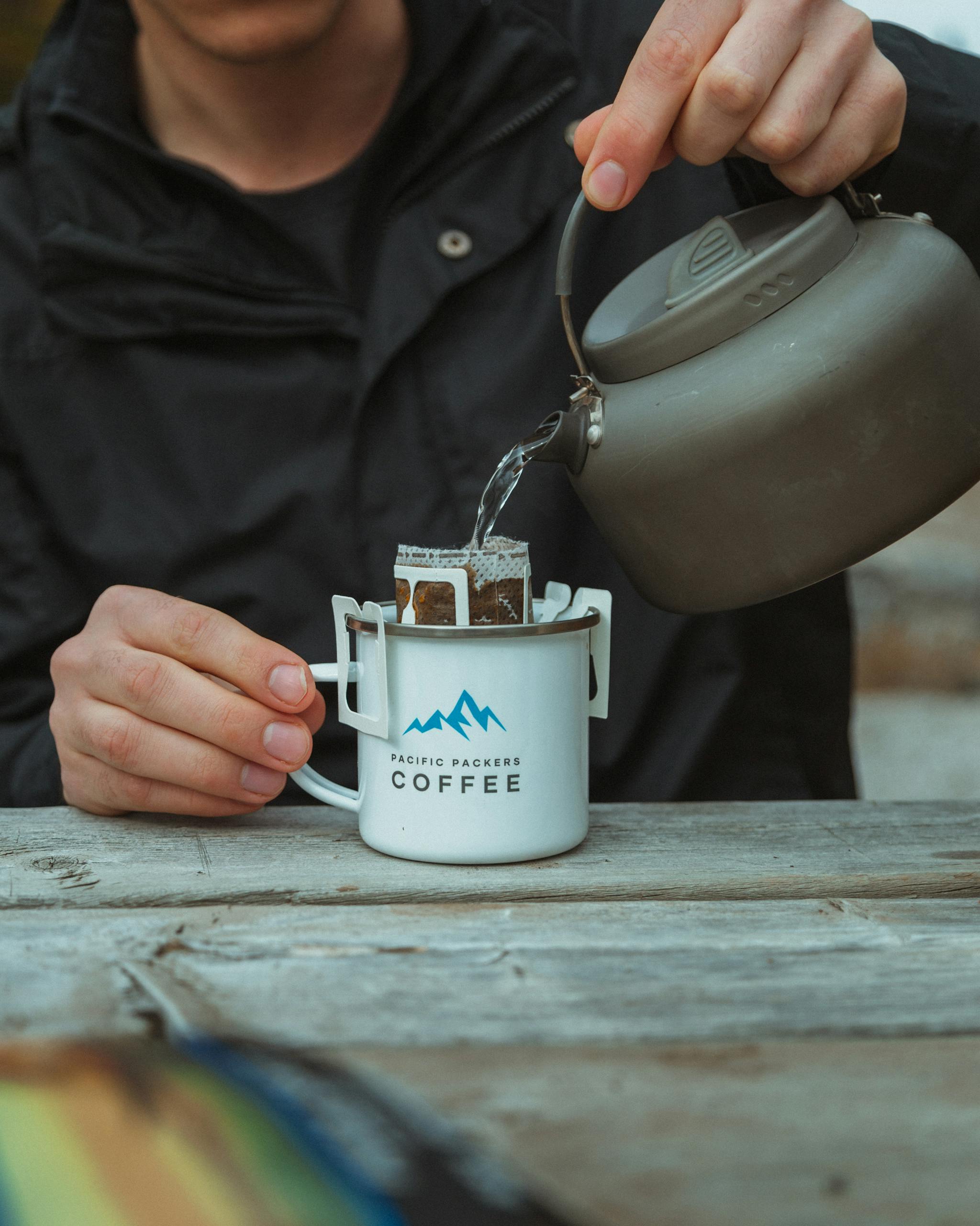 Person pouring hot water into a coffee filter in a camp mug. Perfect for adventurous coffee lovers.